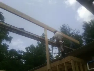 Carpenter setting a ridge beam over a new addition frame — Ice Dam Removal by Roofing Brothers in Oxford Junction