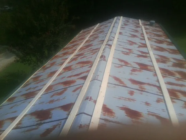 Rusted metal roof panels with new wood purlins before replacement — Storm Damage Roof Repair in Oxford Junction by Roofing Brothers