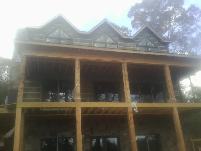 Dormers and porch framing on a large log home under construction — Roof Coating work by our crew in Oxford Junction