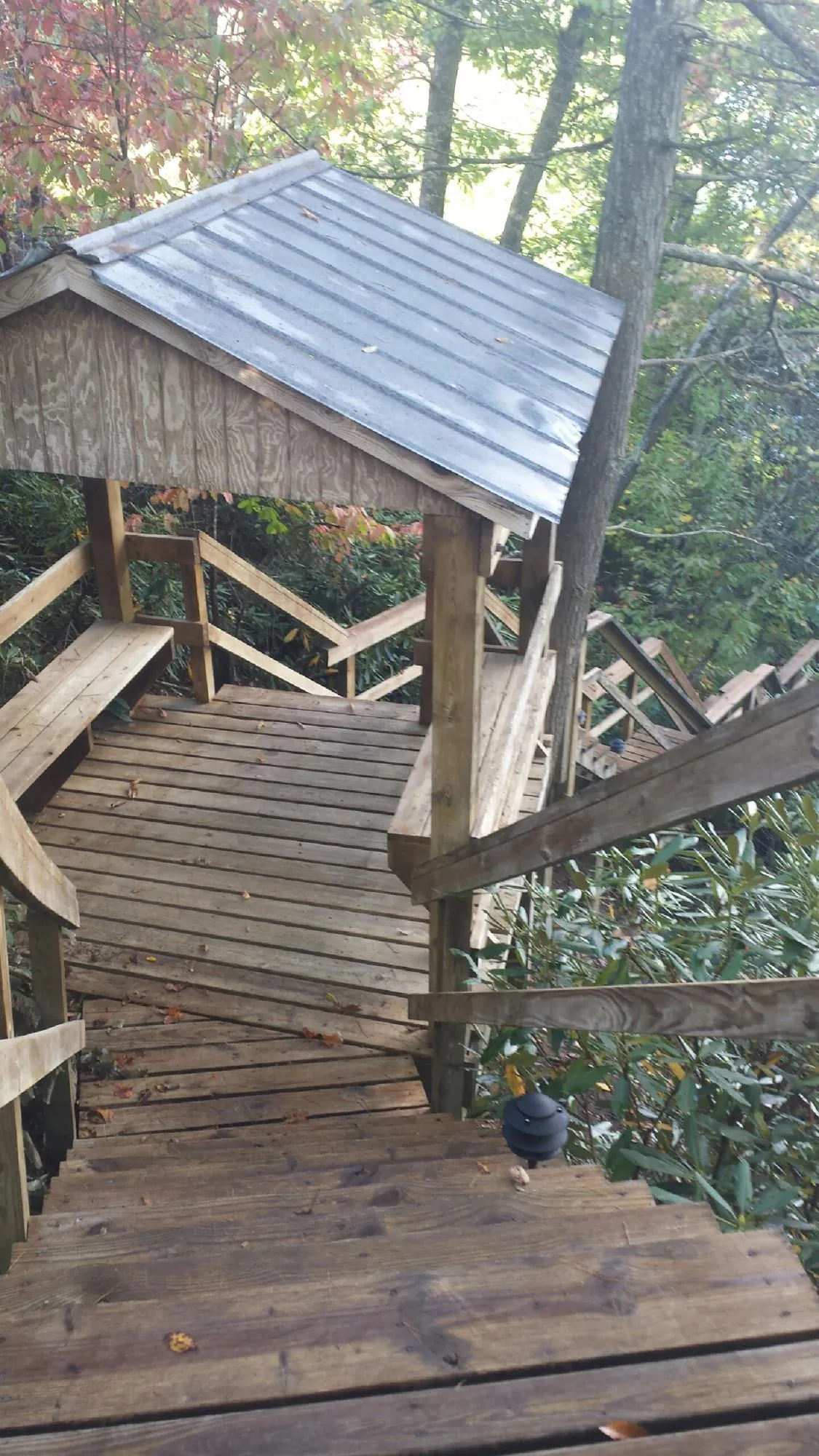 Metal roofed shelter over wooden steps on a wooded walkway — Skylight Repair & Installation work by our crew in Oxford Junction