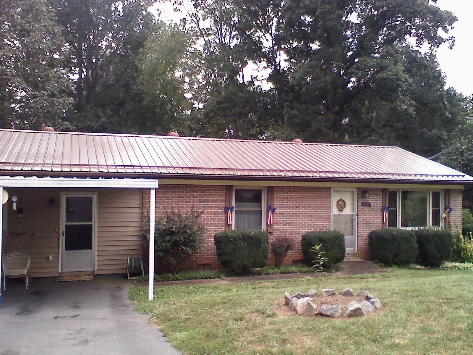 Bronze metal roof and carport on a brick ranch home — Roof Repair work by our crew in Oxford Junction